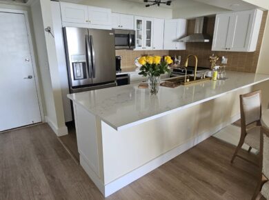 Entry of a remodeled condo unit opening onto a white shaker kitchen with a quartz island