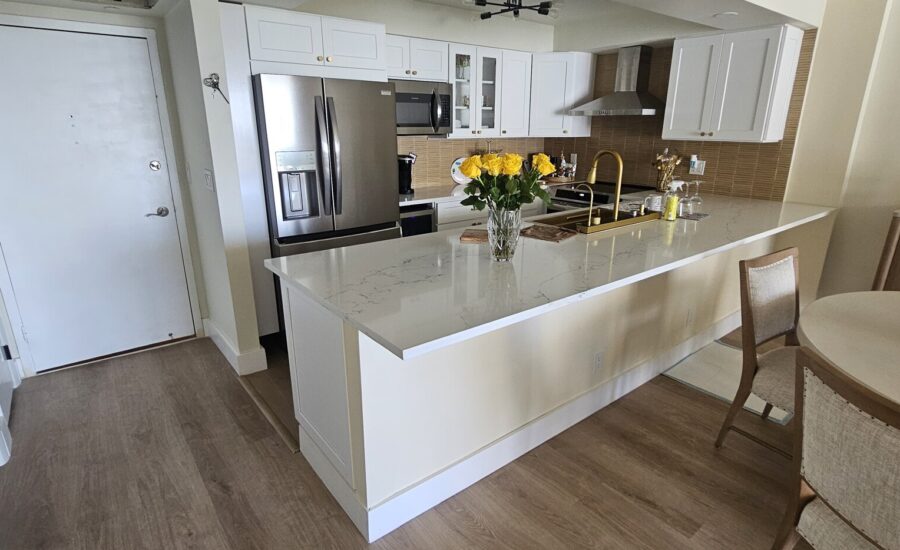 Entry of a remodeled condo unit opening onto a white shaker kitchen with a quartz island