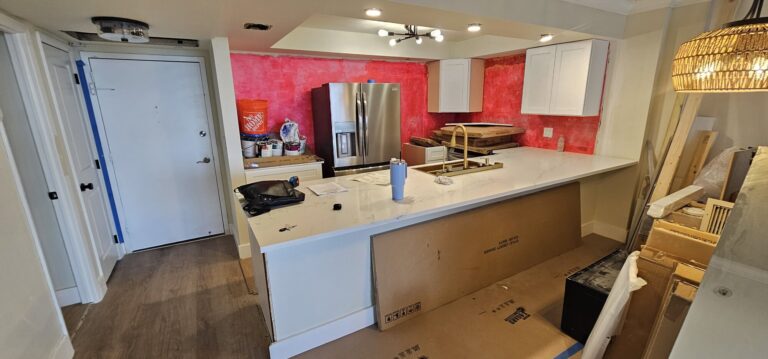 Condo kitchen mid-remodel: white shaker cabinets and quartz island installed, walls still unpainted