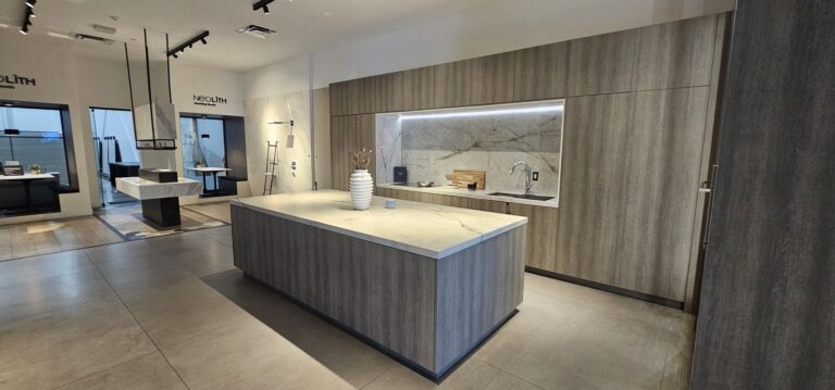Kitchen showroom display with grey wood-grain cabinets and a sintered-stone island