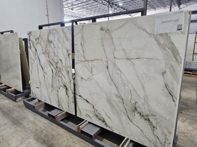 Full-size quartz and porcelain slabs with marble veining in a stone supplier's warehouse