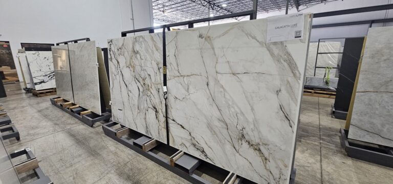 Full-size quartz and porcelain slabs with marble veining in a stone supplier's warehouse